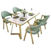 Ensemble de salle à manger bistro moderne et minimaliste avec table finition faux pierre, structure en métal doré et chaises rembourrées pour café