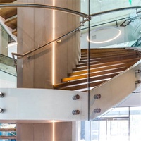 Escalier en verre incurvé avec main courante ronde en acier et limon blanc