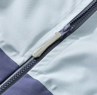 Veste à capuche bicolore bleu glace et violet, poche zippée sur le bras, poches latérales zippées, coupe-vent technique color block