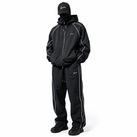 Ensemble de survêtement coupe-vent personnalisé pour homme en nylon noir, veste à capuche et pantalon large avec passepoil blanc, style streetwear et sportif