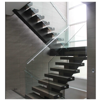 Escalier à monopoutre en acier découpé au laser, marches en noyer massif, système de balustrade en verre