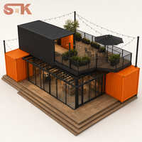 Conteneur modulaire de vente au détail pour boutique éphémère, avec volumes empilables, pavés gris pierre, jardinières noires, sièges extérieurs et espace photo
