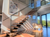 Rampe d'escalier flottante Tanlong moderne en bois dur avec structure centrale et balustrade en verre sans cadre