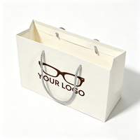 Sac shopping en papier blanc personnalisé avec logo, motif lunettes et poignée tressée argentée pour l'emballage de vente au détail d'optiques et de lunettes