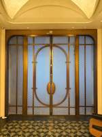 Porte intemporelle d'inspiration Art Déco avec cadre en laiton et verre intime, usinée CNC et brochée, pour couloir d'hôtel de charme