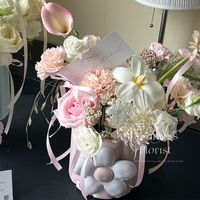 Arrangement floral tridimensionnel mignon de style coréen, avec un joli seau à collation et des petites boîtes en papier rondes, pour une composition florale artistique et une ambiance douillette