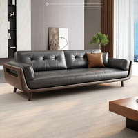 Canapé trois places en cuir pleine fleur gris foncé, dossier capitonné à boutons carrés, accoudoirs en bois découpé, style minimaliste du milieu du siècle