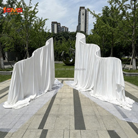 Arche de mariage élégante en métal blanc en forme de S avec rideaux blancs crème pour la décoration de scène
