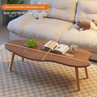 Table basse moderne et simple avec pieds en bois massif et plateau en panneau de densité, forme irrégulière, idéale pour les petits appartements et salons.