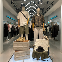 Boutiquede vêtements d'affairesélégants avecaffichage en métalnoir, cintres linéaires et unités de rangement à plusieurs niveaux