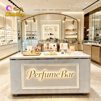 Comptoir de bar à parfums moderne de luxe avec éclairage LED personnalisé, panneau cannelé blanc, cadre doré pour les magasins de cosmétiques et les centres commerciaux