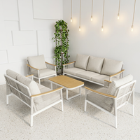 Ensemble de salon d'extérieur moderne en métal blanc, sièges à texture tressée, tables rondes avec accents en bois et coussins gris moelleux, idéal pour le patio