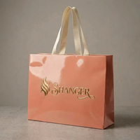 Sac cadeau en papier bordeaux imprimé sur mesure avec logo doré et poignée torsadée en corde, idéal pour l'emballage de vêtements en gros pour boutiques
