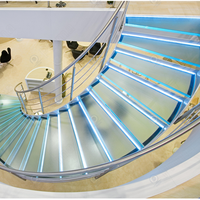 Design d'escalier courbé grandiose avec structure en acier carbone massif et garde-corps en verre transparent pour villa haut de gamme