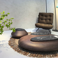 Table basse sculpturale irrégulière avec structure en bois massif et plateau en dalle de pierre, style Wabi-Sabi, inspirée des galets, conçue par des designers pour les villas.