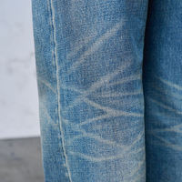 Jeans denim pria streetwear model longgar, 100% katun berkualitas tinggi, dengan logo custom, efek distressed ripped vintage, cuci monkey wash, dan detail twisted whisker.