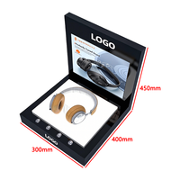 Un présentoir interactif à écran LED en acrylique noir qui met en valeur intelligemment les écouteurs supra-auriculaires avec un éclairage d'ambiance.