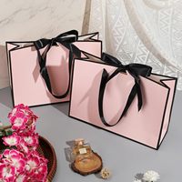 Des arcs roses décorent le sac en papier d'emballage écologique de demoiselle d'honneur de luxe au détail Portable Boutique pour le magasin de vêtements