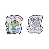Broche en émail « Que laisse-t-on partir ? » avec grenouille espagnole motivante soufflant une pissenlit et un motif spirale dans un trou d'arbre, bijoux et badges