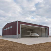 Hangar pour avion privé de couleur bordeaux avec porte coulissante large à l'avant, fenêtres latérales et cour avant en béton