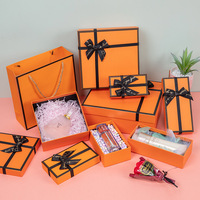 Boîte cadeau en carton magnétique orange avec logo personnalisé, doublée d'éponge, structure rigide écologique, ruban à nœud, laminage mat