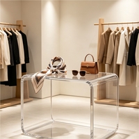 Table basse en acrylique transparent, avec des bords arrondis et un design en cascade, idéale pour la présentation de produits et comme table basse