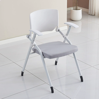 Chaise pliante de conférence grise avec tablette d'écriture, siège rembourré et accoudoirs, pour la formation et les réunions en salle de classe, fournie directement par l'usine