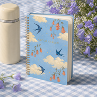 Carnet à spirale LABON Custom Cloud Garden, spirale dorée, ciel bleu, nuages crème, hirondelles bleues, campanules abricot, étoiles dorées