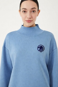Hermosa mujer con una sudadera de cuello alto en un vibrante color rosa intenso, con delicado ribete de encaje y un audazco bordado de águila negra en el pecho. - Product Image 5