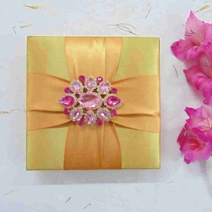 Boîte d'invitation de mariage de luxe aspect soie dorée, ruban croisé en satin ambré, broche en cristal rose, étui en ivoire - Product Image 1
