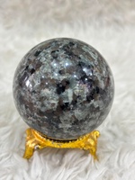Bola Yooperlite dengan badan batu abu-abu berasap, cahaya fluoresen oranye yang berkilau, kelengkungan yang dipoles, dan tampilan mineral yang khas.