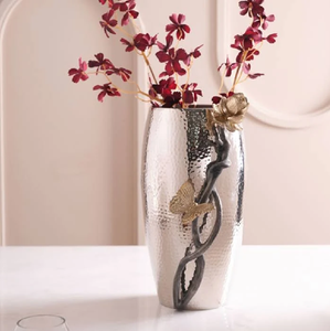 Silver hammered metallic vase with golden butterfly and <b>floral</b> branch accents. Available at wholesale prices. - Product Image 1