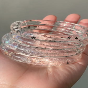 Crystal <b>clear</b> <b>resin</b> bangles infused with fine silver glitter shimmer and tiny star sequins, available at wholesale prices. - Product Image 1