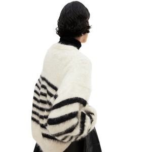 Belle femme modélisant un pull douillet et surdimensionné en fourrure avec des rayures noires audacieuses sur un col roulé noir. - Product Image 3