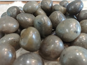 Piedra de labradorita blanca pulida con tonos perlados, superficie lisa y pulida, forma redondeada, textura reflectante subtil para mineral. - Product Image 1