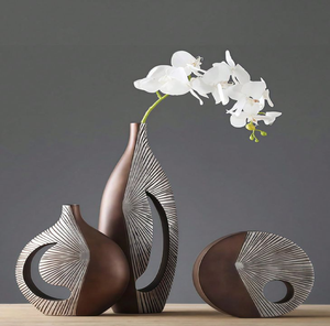 Contemporary bronze geometric hollow vases paired with a single orchid stem, available at wholesale prices. - Product Image 1