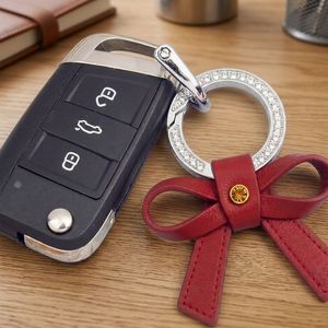 Accesorio de lujo personalizado con lazo rojo y anillo metálico brillante para promoción de joyería, llavero de cuero PU con lazo y dijes. - Product Image 2