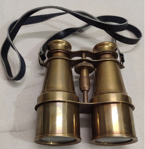 Jumelles militaires classiques en laiton, équipées d'un cordon de cou en cuir foncé, présentées sur une surface en tissu neutre. - Product Image 1
