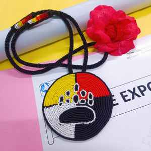 Collier artisanal avec pendentif patte d'ours perlé, sections jaunes, rouges, blanches et noires, et cordon long à suspendre sous la poitrine - Product Image 4