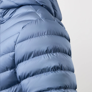 Veste universitaire bleue matelassée à capuche en toile, conçue pour le confort par temps froid, avec un modèle masculin confiant en sa tenue. - Product Image 4