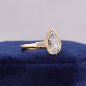 แหวนเพชรทรงลูกแพร์ 1.5 กะรัต ดีไซน์หรูหราโดดเด่นจาก OM GEMS ประดับเพชร 3 เม็ด ได้รับการรับรองจาก IGI ตัวเรือนทองคำขาว 14k เหมาะสำหรับงานแต่งงาน - Product Image 3