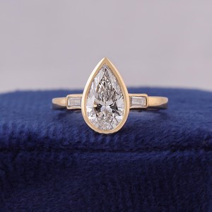 แหวนเพชรทรงลูกแพร์ 1.5 กะรัต ดีไซน์หรูหราโดดเด่นจาก OM GEMS ประดับเพชร 3 เม็ด ได้รับการรับรองจาก IGI ตัวเรือนทองคำขาว 14k เหมาะสำหรับงานแต่งงาน - Product Image 1