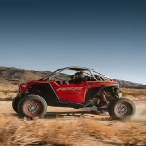Véhicule tout-terrain rouge RZR avec cage de sécurité noire et pneus larges pour terrain désertique - Product Image 2
