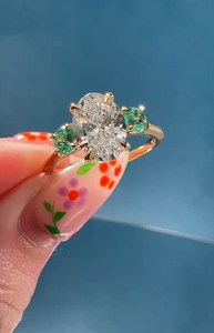 Bague à trois pierres en or 14 carats avec diamant ovale de 3,01 carats cultivé en laboratoire et pierres précieuses vertes rondes latérales, idéale pour fiançailles, promesse, fête ou comme cadeau. - Product Image 2