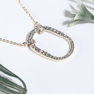 Breloque classique en cristal pavé de forme géométrique en forme de trombone, mettant en valeur un pendentif ovale contemporain inspiré d'un mousqueton, bijou à chaîne à maillons. - Product Image 1