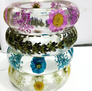 Impresionantes brazaletes apilados de resina transparente que exhiben margaritas secas de colores y brillantes copos de oro, disponibles a precios de mayorista. - Product Image 4