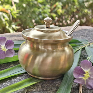Charming antique brass ghee <b>pot</b> rests gracefully on a natural stone with a custom spoon. Available at wholesale price. - Product Image 1