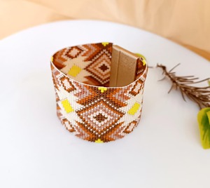 Bracelet manchette perlé fait main à motif géométrique aux tons terreux et accents jaunes, accessoire de mode - Product Image 1
