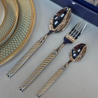 Ensemble de couverts de luxe en acier inoxydable doré poli, avec une conception moderne de tête de cuillère ronde à col fin.