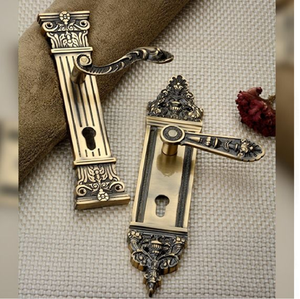 Manijas de palanca de bronce antiguo con motivos clásicos y escuteces para cerraduras a juego. Disponible a precios de mayorista. - Product Image 1